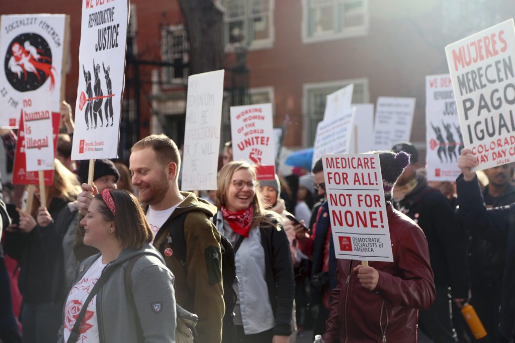 Denver DSA members marching with red flags and signs for Democratic Socialism